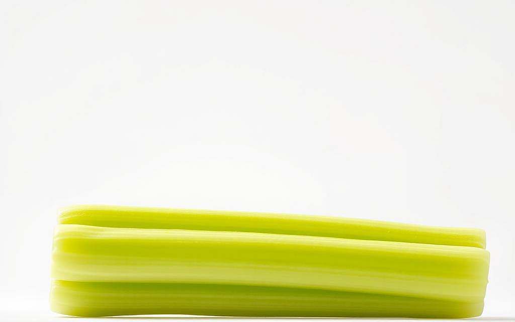 Detailed close-up of a fresh, crisp celery stalk against a clean, minimalist white background. The celery has a vibrant green color and a succulent, textured surface. Capture the unique cellular structure and intricate veining of the celery, showcasing its nutrient-rich composition. Employ soft, diffused lighting to create a clean, modern aesthetic, highlighting the celery's natural beauty and purity. Shoot from a low angle to emphasize the celery's upright, towering presence, creating a sense of power and importance. Ensure a sharp, high-resolution focus to bring out the finest details of the celery's mineral-rich flesh.
