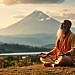 A serene and contemplative scene of Advaita Vedanta, the spiritual philosophy of non-duality. In the foreground, a sage sits cross-legged, eyes closed in deep meditation, radiating an aura of tranquility. The middle ground features a picturesque landscape of rolling hills, lush vegetation, and a tranquil lake reflecting the sky above. In the background, a majestic mountain range stands tall, its peaks illuminated by a warm, golden light, symbolizing the transcendent nature of the Absolute. The overall atmosphere is one of introspection, unity, and the dissolution of the individual self into the universal consciousness. Soft, diffused lighting creates a dreamlike, ethereal quality, inviting the viewer to contemplate the essence of Advaita Vedanta.