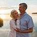 A senior couple lovingly embraces by a serene lake during a beautiful sunset.
