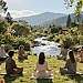 A serene, meditative scene illustrating "Meditation and Mindfulness" in a tranquil environment. In the foreground, a diverse group of individuals in modest, casual attire are engaged in meditation, seated in a garden surrounded by lush greenery and blooming flowers. In the middle ground, a gently flowing river reflects the sunlight, creating mesmerizing ripples that enhance the calm atmosphere. The background features soft, distant mountains under a clear blue sky, symbolizing tranquility and peace. Warm, soft lighting bathes the scene, casting gentle shadows, and creating a serene mood. The camera angle is slightly elevated, providing a panoramic view of this peaceful setting, inviting viewers to feel the stillness and the positive energy derived from mindfulness practices.